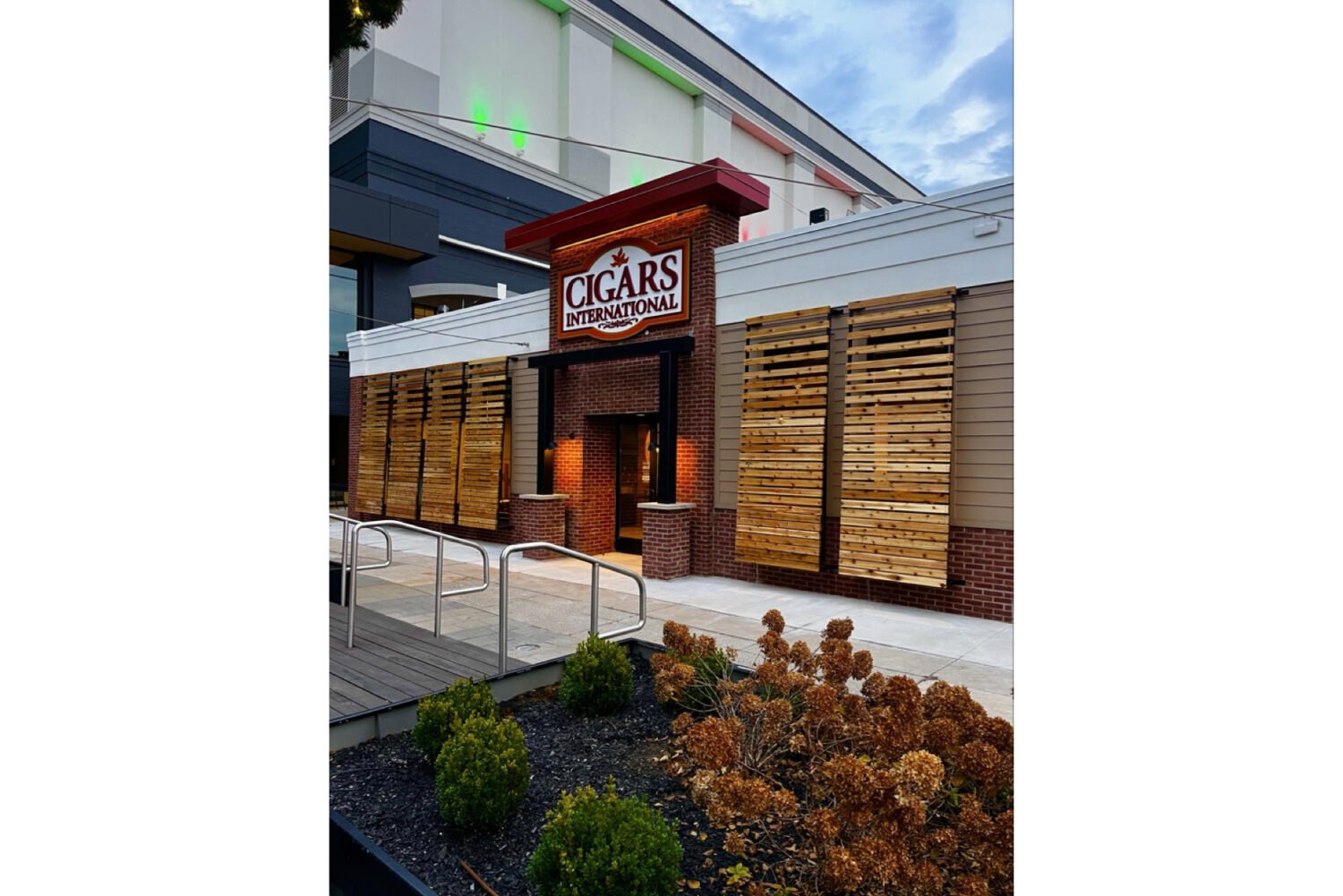 گسترش امپراتوری سیگار برگ : راه‌اندازی فروشگاه جدید Cigars International در نیوپورت، کنتاکی مقدمه : فراتر از یک فروشگاه جدید در دنیای پویا و رقابتی صنعت سیگار برگ، هر حرکت استراتژیک از سوی بازیگران بزرگ، پیامدهای عمیقی برای آینده بازار دارد. اخیراً، شرکت Cigars International (CI)، که به عنوان بزرگترین فروشنده سیگار برگ در جهان شناخته می‌شود، از افتتاح جدیدترین شعبه خود در شهر نیوپورت، ایالت کنتاکی، خبر داد. این خبر در نگاه اول ممکن است صرفاً یک توسعه جغرافیایی دیگر به نظر برسد، اما تحلیل دقیق‌تر نشان می‌دهد که این اقدام، گامی هوشمندانه و چندلایه برای تقویت سلطه این شرکت و نشان دادن قدرت شرکت مادرش، Scandinavian Tobacco Group (STG)، است. این مقاله به بررسی جامع این رویداد می‌پردازد و آن را از منظر استراتژی خرده‌فروشی، اهمیت مکانی، و روندهای کلان صنعت سیگار برگ تحلیل می‌کند. نگاهی دقیق‌تر به فروشگاه نیوپورت؛ استراتژی مکان و تجربه مشتری فروشگاه جدید Cigars International در آدرس 1 Levee Way, P-106, Newport, Ky. واقع شده است. این مکان تنها یک آدرس نیست، بلکه یک انتخاب استراتژیک هوشمندانه است. این فروشگاه در منطقه "Newport on the Levee" قرار دارد؛ یک مرکز خرید، سرگرمی و رستوران‌های پرجنب‌وجوش که در کنار رود اوهایو واقع شده و تنها چند دقیقه با شهر سینسیناتی اوهایو فاصله دارد. این موقعیت‌جغرافیایی، فروشگاه را در قلب یک منطقه سه‌ایالتی (اوهایو، کنتاکی و ایندیانا) قرار می‌دهد که پتانسیل بازار بالایی برای علاقه‌مندان به سیگار برگ دارد. فضای داخلی فروشگاه با مساحت ۵,۷۰۰ فوت مربع (حدود ۵۳۰ متر مربع)، طراحی شده تا تجربه‌ای فراتر از یک خرید ساده ارائه دهد. ویژگی‌های کلیدی آن شامل موارد زیر است: 1. بار کامل (Full-Service Bar): حضور یک بار با سرویس کامل، فضا را از یک فروشگاه صرف به یک مرکز اجتماعی تبدیل می‌کند. مشتریان می‌توانند در کنار لذت بردن از سیگار برگ مورد علاقه خود، از نوشیدنی‌های متنوع نیز بهره‌مند شوند. این ویژگی، زمان اقامت مشتریان را افزایش داده و تعاملات اجتماعی را ترویج می‌دهد. 2. هومیدور سرپوشیده (Walk-in Humidor): قلب تپنده هر فروشگاه سیگار برگ، هومیدور آن است. یک هومیدور سرپوشیده و بزرگ به مشتریان این امکان را می‌دهد که در محیطی با رطوبت و دمای کنترل‌شده، در میان مجموعه‌ای گسترده از سیگار برگ‌ها قدم بزنند، بوی توتون‌های مختلف را استشمام کنند و انتخاب خود را با دقت و آگاهی بیشتری انجام دهند. 3. اتاق کشیدن داخلی (Indoor Lounge): این فضا برای آرامش و لذت بردن از سیگار برگ طراحی شده است. مبلمان راحت، دکوراسیون شیک و فضایی آرام، محیطی ایده‌آل برای تفریح، گفتگو با دوستان یا ملاقات با دیگر علاقه‌مندان فراهم می‌کند. 4. فضای نشیمن دوطبقه در فضای باز (Two Levels of Outdoor Seating): با توجه به موقعیت فروشگاه در کنار رود اوهایو، فضای نشیمن در فضای باز یک مزیت فوق‌العاده است. این ویژگی به مشتریان اجازه می‌دهد تا در هوای آزاد و با منظره‌ای زیبا از سیگار برگ خود لذت ببرند. نکته جالب توجه این است که برخلاف اکثر فروشگاه‌های CI که به صورت ساختمان‌های مستقل و جدید ساخته می‌شوند، این شعبه در یک مرکز تجاری موجود مستقر شده است. این رویکرد می‌تواند به معنای کاهش هزینه‌های اولیه ساخت‌وساز و دسترسی سریع‌تر به جریان بالای مشتریان در یک منطقه پرتردد باشد. اسکات واسکو (Scott Vasko)، معاون امور خرده‌فروشی Cigars International، در یک بیانیه مطبوعاتی به درستی این فضا را فراتر از یک محل خرید توصیف می‌کند: "ما از آوردن تجربه Cigars International به Newport on the Levee بسیار هیجان‌زده‌ایم. این فروشگاه فقط برای خرید سیگار برگ‌ های عالی نیست؛ بلکه در مورد جامعه، آرامش و خلق خاطرات است. تیم ما فضایی ایجاد کرده است که در آن می‌توانید سیگار برگ مورد علاقه بعدی خود را کشف کنید، با دوستان خود آرامش کنید و از همراهی سایر علاقه‌مندان به سیگار برگ لذت ببرید." این جمله، اصل کلیدی استراتژی مدرن CI را به نمایش می‌گذارد: فروش تجربه، نه فقط محصول. Cigars International غول چندکاناله خرده‌فروشی برای درک اهمیت افتتاح فروشگاه نیوپورت، باید با مدل کسب‌وکار Cigars International آشنا شویم. CI صرفاً یک زنجیره فروشگاه فیزیکی نیست؛ بلکه یک غول چندکاناله (Omnichannel) است که به تسلط بر تمام نقاط تماس با مشتری افتخار می‌کند. * ریشه‌ها در فروش از راه دور: CI کار خود با کسب‌وکار فروش از طریق پست‌الکترونیک و کاتالوگ آغاز کرد. در دورانی که اینترنت هنوز فراگیر نشده بود، کاتالوگ‌های رنگین و قطور CI، پنجره‌ای به دنیای سیگار برگ برای هزاران علاقه‌مند در سراسر آمریکا بودند. این شرکت با ارائه قیمت‌های رقابتی و مجموعه‌ای گسترده، پایه‌های امپراتوری خود را بر این بنا نهاد. * انقلاب اینترنتی: با ظهور اینترنت، CI به سرعت یکی از پیشگامان فروش آنلاین سیگار برگ شد. وب‌سایت آن، Cigars.com، به یکی از جامع‌ترین منابع برای خرید، بررسی و یادگیری در مورد سیگار برگ تبدیل شد. * گسترش فیزیکی: با وجود موفقیت چشمگیر در فضای دیجیتال، CI اهمیت حضور فیزیکی را درک کرد. فروشگاه‌های فیزیکی به چند دلیل حیاتی هستند: 1. نمایشگاه زنده: این فروشگاه‌ها به عنوان نمایشگاه‌های زنده برای محصولات آنلاین عمل می‌کنند. مشتریان می‌توانند قبل از خرید آنلاین، محصولات را از نزدیک لمس کنند و با مشاوران صحبت نمایند. 2. ایجاد جامعه: اتاق‌های کشیدن (Lounge) در فروشگاه‌ها، قلب تپنده جامعه علاقه‌مندان به سیگار برگ هستند. این فضاها جایی هستند که روابط شکل می‌گیرند، تجربیات به اشتراک گذاشته می‌شود و وفاداری به برند عمیق‌تر می‌شود. 3. تجربه حسی: سیگار برگ یک محصول کاملاً حسی است. بوی توتون، بافت برگ، وزن و ظاهر آن—all of these things matter. فروشگاه فیزیکی تنها جایی است که این تجربه کامل را می‌توان ارائه داد. فروشگاه نیوپورت چهاردهمین شعبه CI است که اکثر آن‌ها در مناطق استراتژیک مانند فلوریدا، پنسیلوانیا و تگزاس متمرکز شده‌اند. این پراکندگی نشان‌دهنده استراتژی هدفمند برای پوشش بازارهای کلیدی با جمعیت بالای علاقه‌مندان به سیگار برگ است. قدرت پشت صحنه؛ Scandinavian Tobacco Group (STG) هیچ تحلیلی از Cigars International بدون اشاره به شرکت مادر آن، Scandinavian Tobacco Group (STG)، کامل نیست. STG یک شرکت چندملیتی دانمارکی است که یکی از بزرگترین تولیدکنندگان محصولات توتونی در جهان است و حضور عمیقی در صنعت سیگار برگ دارد. STG با یک استراتژی هوشمندانه ادغام عمودی (Vertical Integration)، کسب‌وکار خود را گسترش داده است. این شرکت نه تنها برندهای تولیدی متعددی را در مالکیت دارد، بلکه با خرید بزرگترین خرده‌فروشان مانند Cigars International، Thompson Cigar و Cigar.com، کانال توزیع و فروش مستقیم به مصرف‌کننده نهایی را نیز تحت کنترل خود درآورده است. این استراتژی به STG اجازه می‌دهد تا از مزرعه توتون تا لبان مصرف‌کننده، زنجیره ارزش را کنترل کند. پورتفولیو عظیم برندهای STG: STG مالک برخی از شناخته‌شده‌ترین برندهای سیگار برگ در بازار آمریکا است که شامل موارد زیر می‌شود: * Cohiba و Partagas (نسخه‌های غیر کوبایی): این برندها که از نظر تاریخی به کوبا تعلق دارند، در نسخه‌های غیرکوبایی خود توسط General Cigar (زیرمجموعه STG) تولید و به فروش می‌رسند و به عنوان برندهای پریمیوم و شناخته‌شده در سطح جهانی محسوب می‌شوند. * Macanudo: یکی از پرفروش‌ترین برندهای سیگار برگ ملایم در جهان که به عنوان یک انتخاب کلاسیک برای سیگار برگ‌کش‌های مبتدی و باتجربه شناخته می‌شود. * Alec Bradley: برندی که به خاطر ترکیب‌های نوآورانه و باکیفیت خود شهرت دارد و جوایز متعددی را از آن خود کرده است. * CAO: برندی که برای ترکیب‌های جسورانه و متنوع خود، به ویژه استفاده از توتون‌های مناطق مختلف جهان، شهرت دارد. * Room101: برندی با هویتی مدرن و جسورانه که طرفداران پروپاقرص خود را دارد. علاوه بر این، STG شرکت‌های خرده‌فروشی دیگری مانند Thompson Cigar, Cigar Bid, Pipes and Cigars, و Club Macanudo را نیز در مالکیت دارد. این شبکه گسترده، به STG قدرت بی‌نظیری در قیمت‌گذاری، بازاریابی و توزیع می‌دهد. جالب است بدانید که STG پورتفولیو برندهای خود را بین دو تیم فروش جداگانه تقسیم کرده است: General Cigar Co. و Forged Cigar Co. این اقدام استراتژیک احتمالاً برای مدیریت بهتر کانال‌های فروش مختلف، جلوگیری از تداخل فروش و تمرکز بر بخش‌های متفاوت بازار (مثلاً خرده‌فروشی در مقابل فروش عمده) انجام شده است. اهمیت استراتژیک راه‌اندازی نیوپورت در صنعت سیگار برگ افتتاح فروشگاه نیوپورت در بستر روندهای کلان صنعت سیگار برگ معنادار است: 1. اعتماد به خرده‌فروشی فیزیکی در عصر دیجیتال: در دنیایی که فروش آنلاین تسلط یافته، سرمایه‌گذاری سنگین یک غول دیجیتال مانند CI در یک فروشگاه فیزیکی لوکس، این پیام را می‌دهد که تجربه حضوری و اجتماعی هنوز اهمیت حیاتی دارد، به‌ویژه برای محصولات لوکس و سرگرمی‌هایی مانند سیگار برگ. 2. رقابت یا همزیستی؟ این فروشگاه کمتر از یک مایل با The Party Source فاصله دارد؛ یک فروشگاه نوشیدنی عظیم به مساحت ۱۱۳,۰۰۰ فوت مربع که حجم قابل توجهی سیگار برگ نیز می‌فروشد. این نزدیکی می‌تواند یک حرکت مستقیم رقابتی برای جذب سهم بازار باشد، اما می‌تواند به ایجاد یک "قطب سیگار برگ" در منطقه نیز منجر شود. جایی که علاقه‌مندان برای گشت‌وگذار و مقایسه به هر دو مرکز مراجعه کنند و در نهایت به رشد کل بازار در آن منطقه کمک شود. 3. تمرکز بر تجربه "مکان سوم": فروشگاه‌هایی مانند CI نیوپورت، فراتر از یک محل خرید، به "مکان سوم" برای مشتریان خود تبدیل می‌شوند (مکان اول: خانه، مکان دوم: محل کار). این فضاها برای آرامش، ارتباط اجتماعی و تعلق به یک جامعه طراحی شده‌اند. این حس تعلق، وفاداری به برند را به سطحی فراتر از قیمت و محصول می‌رساند. نتیجه‌گیری : یک حرکت شطرنج هوشمندانه افتتاح فروشگاه Cigars International در نیوپورت، کنتاکی، بسیار فراتر از افزودن یک شعبه جدید به نقشه این شرکت است. این یک حرکت شطرنج حساب‌شده است که چندین هدف را به طور همزمان دنبال می‌کند: * تسلط بر یک منطقه استراتژیک: با حضور در قلب منطقه سه‌ایالتی سینسیناتی. * تقویت برند از طریق تجربه: با ارائه یک فضای لوکس و اجتماعی که وفاداری مشتری را جلب می‌کند. * نمایش قدرت شرکت مادر (STG): و تأکید بر توانایی آن برای سرمایه‌گذاری‌های کلان و هدایت روندهای بازار. * تأیید مدل خرده‌فروشی چندکاناله: و اثبات اینکه موفقیت در دنیای مدرن نیازمند ترکیبی هوشمندانه از قدرت آنلاین و جذابیت فیزیکی است. این فروشگاه جدید، قطعه ای از دنیای مدرن سیگار برگ است؛ دنیایی که در آن ادغام عمودی، تجربه مشتری و جامعه‌سازی، کلیدهای اصلی سلطه و موفقیت هستند. با برگزاری مراسم افتتاحیه بزرگ در تاریخ ۶ دسامبر، Cigars International نه تنها یک فروشگاه جدید، بلکه یک بیانیه قدرتمند در مورد آینده این صنعت به نمایش می‌گذارد. آینده‌ای که در آن، امپراتوری‌های سیگار برگ همچنان بر بستر استراتژی‌های هوشمندانه و سرمایه‌گذاری‌های جسورانه گسترش خواهند یافت.